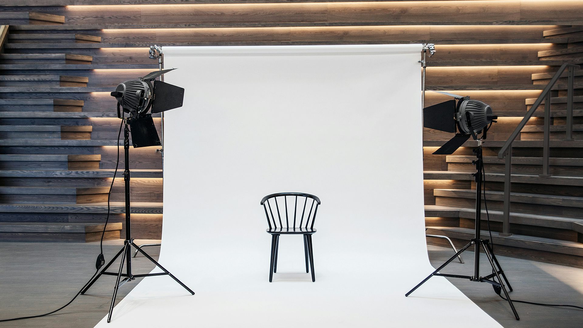 Svart pinnstol med böjd rygg (Edda från Torkelsson). Stolen står placerad på en vit fotoduk som hänger på en ställning. Två kameralampor på stativ är riktade mot den.