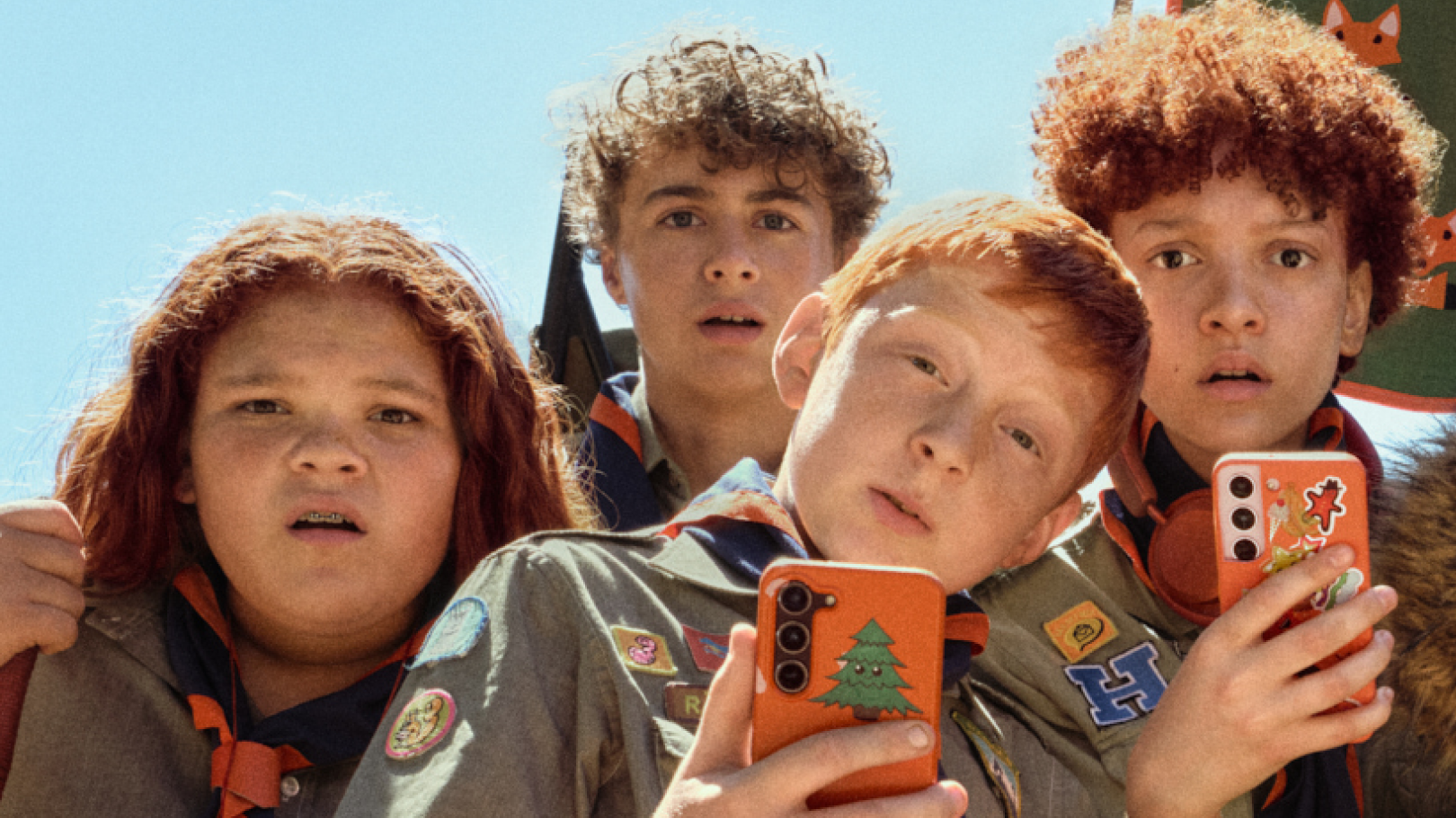 Fyra ungdomar med gröna scout-kläder kollar förvånat in i kameran.